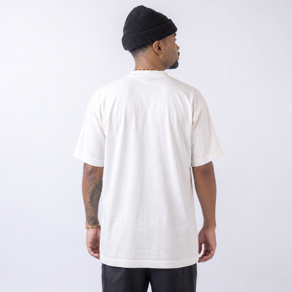 Camiseta Oversized WNC Lisa Off White em vista traseira, com o mesmo modelo de gorro do ensaio da cor. Imagem complementar gerada digitalmente.