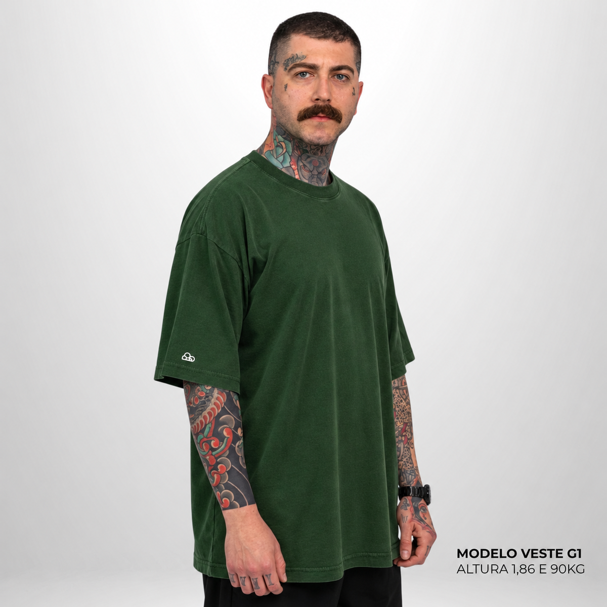 Camiseta Oversized WNC Lisa Verde Militar em vista lateral, com o modelo do ensaio original da cor. Imagem complementar gerada digitalmente.
